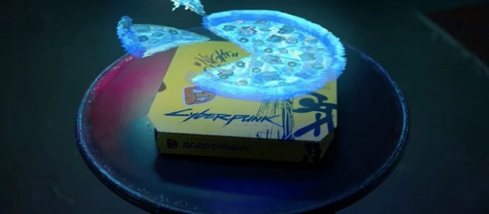 «Додо» выпустила пиццу по Cyberpunk 2077 с соусом «Киберкола барбекю» и халявными стикерами. А желтая коробка превращается в голограмму